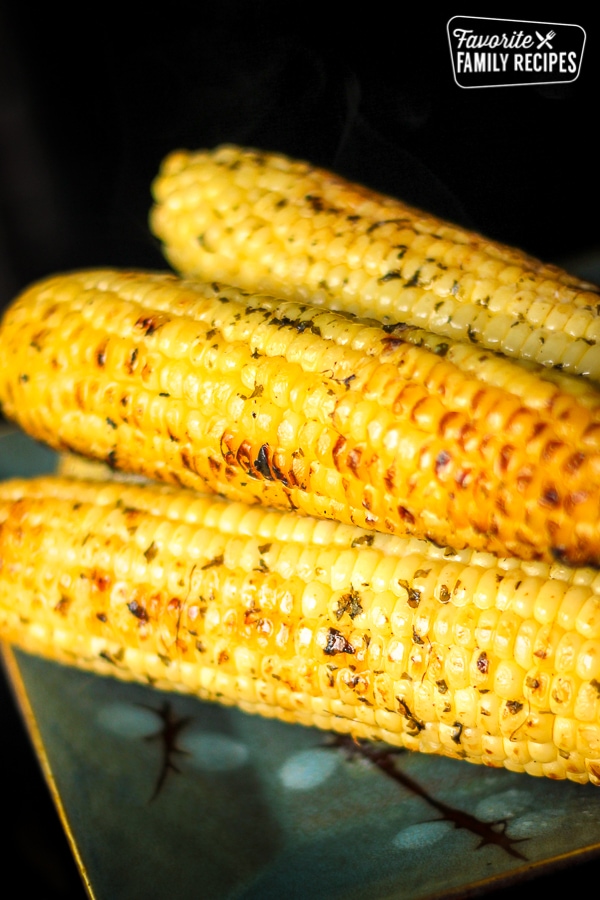 Grilled Cilantro Lime Corn on the Cob stacked on top of each other on a plate.