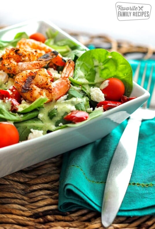 Grilled Shrimp Salad with Cilantro Verde Dressing in a white bowl with a fork on the side.