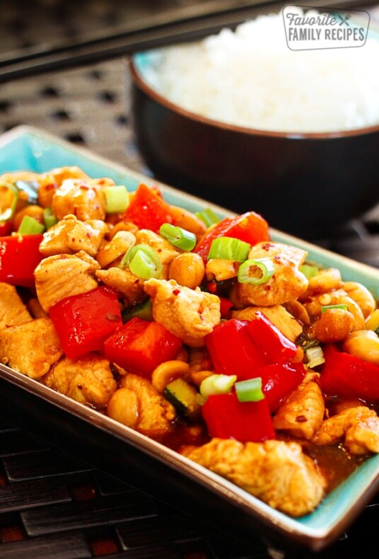 Kung Pao Chicken on a blue tray with a side of white rice in the background.