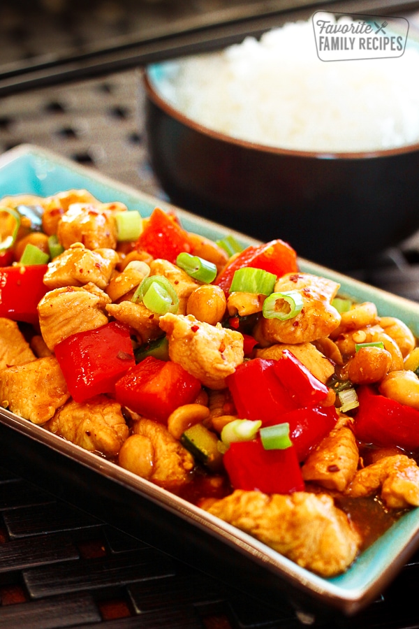 Kung Pao Chicken on a blue tray with a side of white rice in the background.