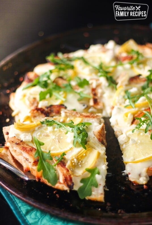 Lemon Chicken Pizza with a slice poking out on a pizza pan