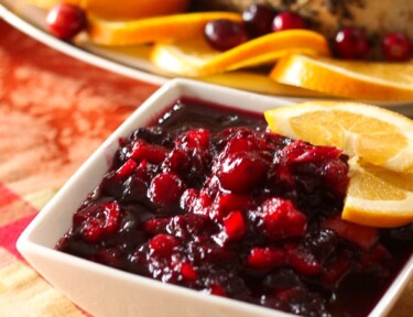 Low Sugar Cranberry Sauce topped with ornage slices in a white Serving Dish