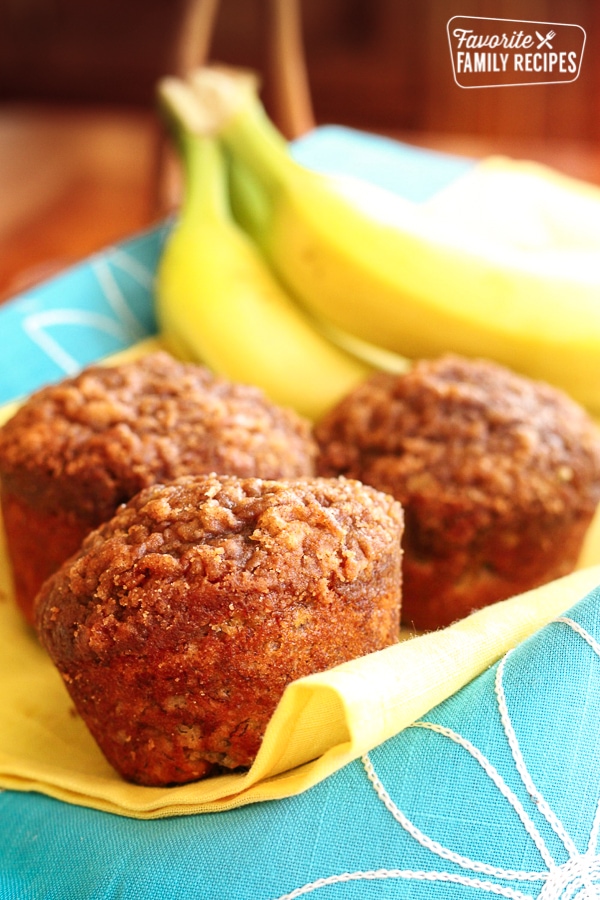 Healthy Banana Muffins on a yellow and blue cloth with bananas in the background.