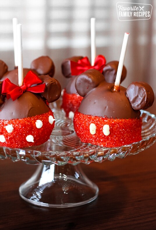 4 Mickey and Minnie Caramel Apples on a glass tray.