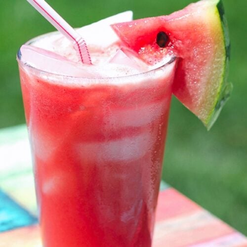 A glass of Melonade with a straw and watermelon slice.
