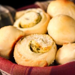 Moms Rolls and Pesto Rolls in a bread basket with a plaid napkin