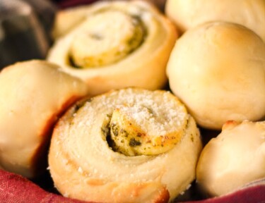 Moms Rolls and Pesto Rolls in a bread basket with a plaid napkin