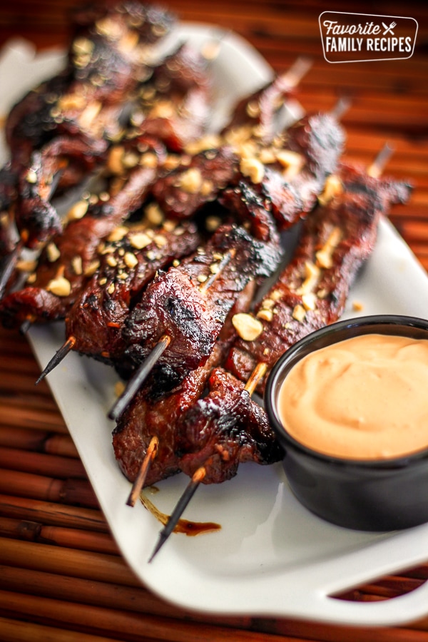 Mongolian Beef Satay with a side of dipping sauce on a white tray.