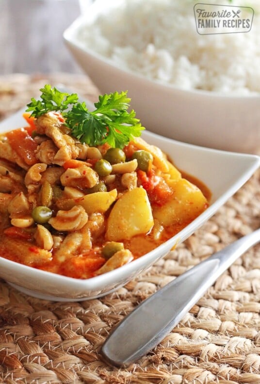 Chicken Panang curry in a white bowl with a spoon on the side.