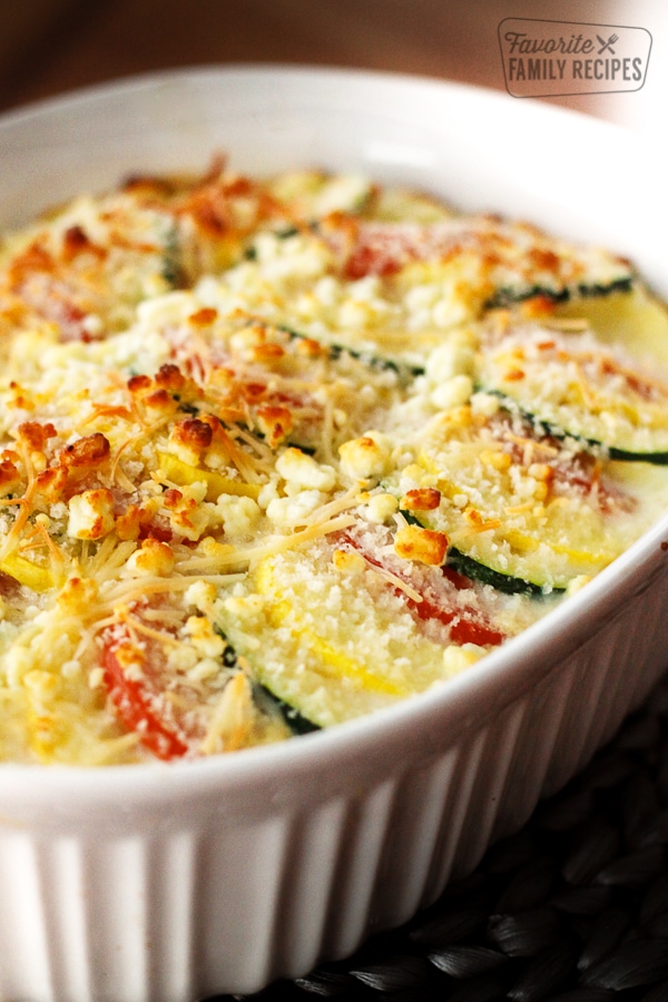 Parmesan Squash Casserole with layers of sliced squash and zucchini in a white ceramic baking dish