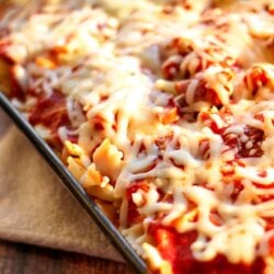 Pasta Sausage Bake topped with melted cheese in a glass pan