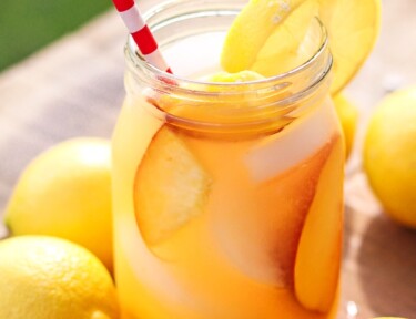 Easy Peach Lemonade in a mason jar with a red and white striped straw sticking out.