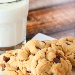 A plate of peanut butter chocolate chip cookies with a glass of milk to the side