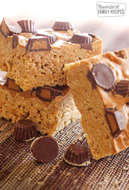Peanut Butter Cup Rice Krispie Treats stacked on top of each other with peanut butter cups on the side.