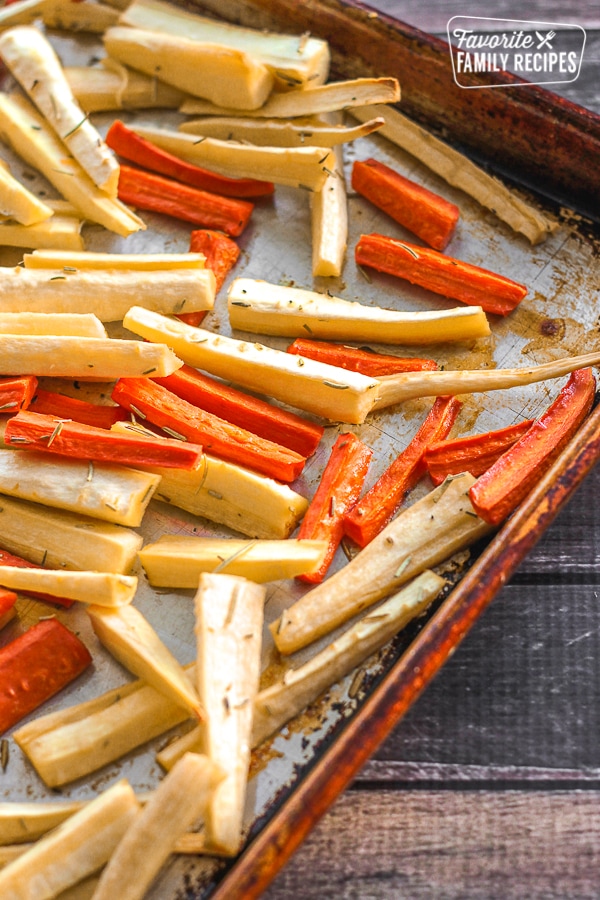 Parsnips and carrots roasted on a baking sheet. 
