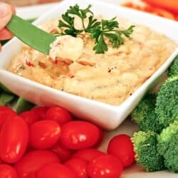 Roasted Red Pepper Dip in a dish surrounded by veggies.