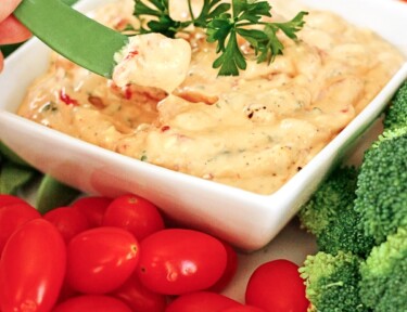 Roasted Red Pepper Dip in a dish surrounded by veggies.