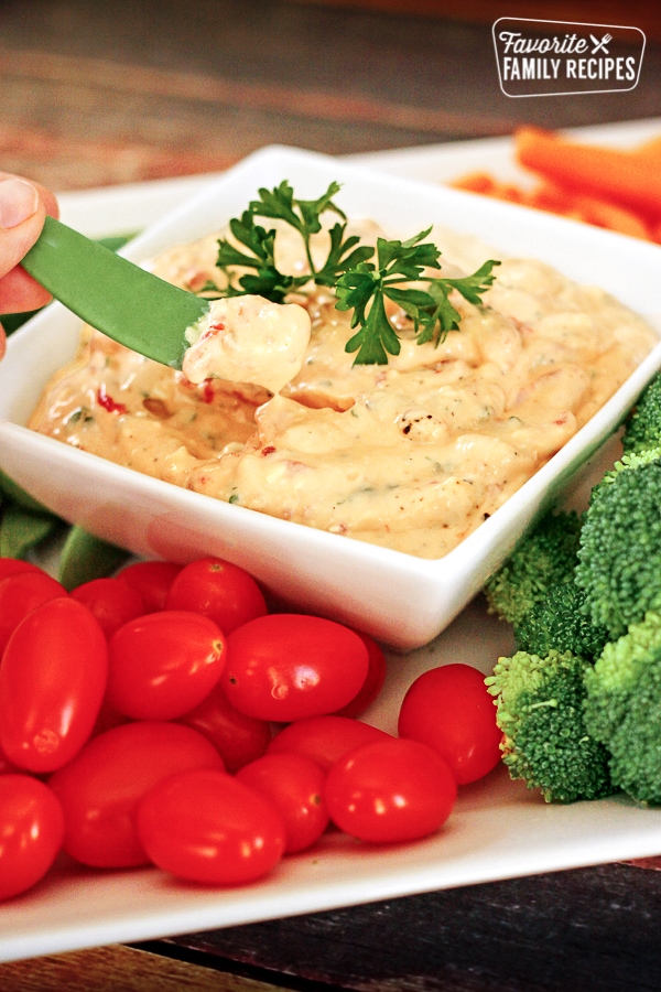 Roasted Red Pepper Dip in a dish surrounded by veggies.