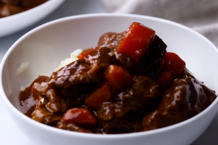 Thick and Beefy Danish Goulash served over mashed potatoes in a bowl.