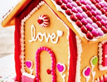 Valentine's Day Gingerbread house decorated with pink and red frosting and heart candies