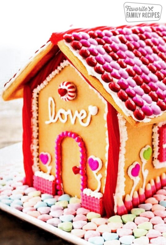Valentine's Day Gingerbread house decorated with pink and red frosting and heart candies