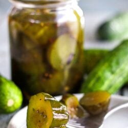 Virginia chunk sweet pickles in a jar and a pickle outside of the jar on a white plate with a fork in a pickle.