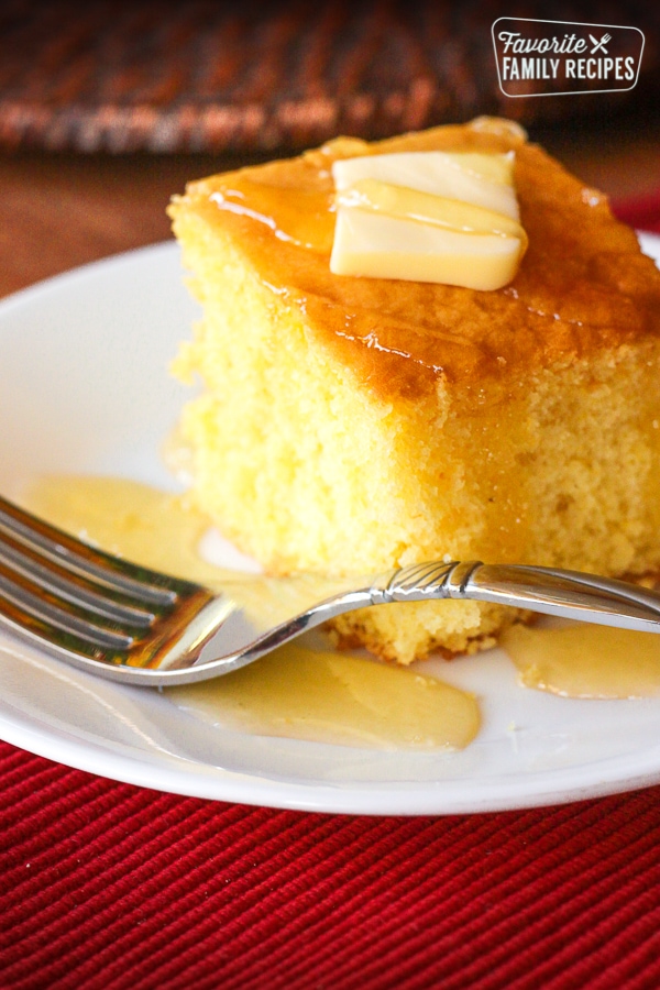 Eine Scheibe Cake Mix Cornbread auf einem weißen Teller neben einer Gabel.