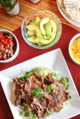 Grilled Carne Asada on a plate with avocado, cheese, and salsa on the side.