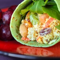 Chicken Salad Curry Wrap with grapes on the side on a red plate.
