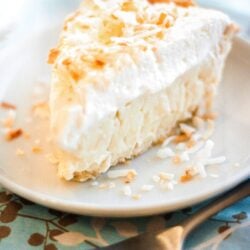 Slice of Coconut Cream Pie on a white Plate with a fork to the side.