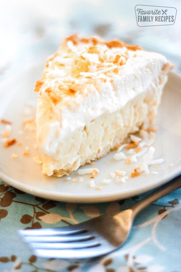 Slice of Coconut Cream Pie on a white Plate with a fork to the side.