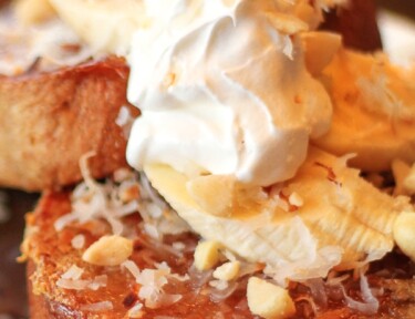 Coconut Macadamia Nut French Toast on a plate topped with whipped cream.