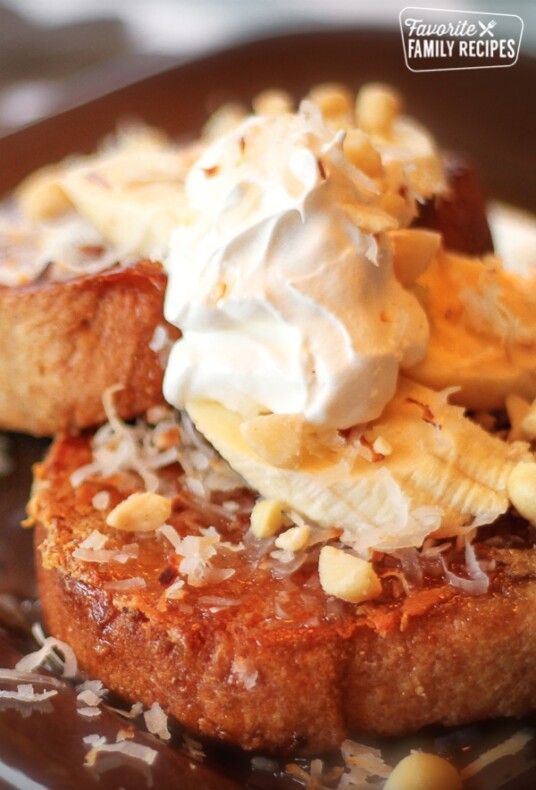 Coconut Macadamia Nut French Toast on a plate topped with whipped cream.