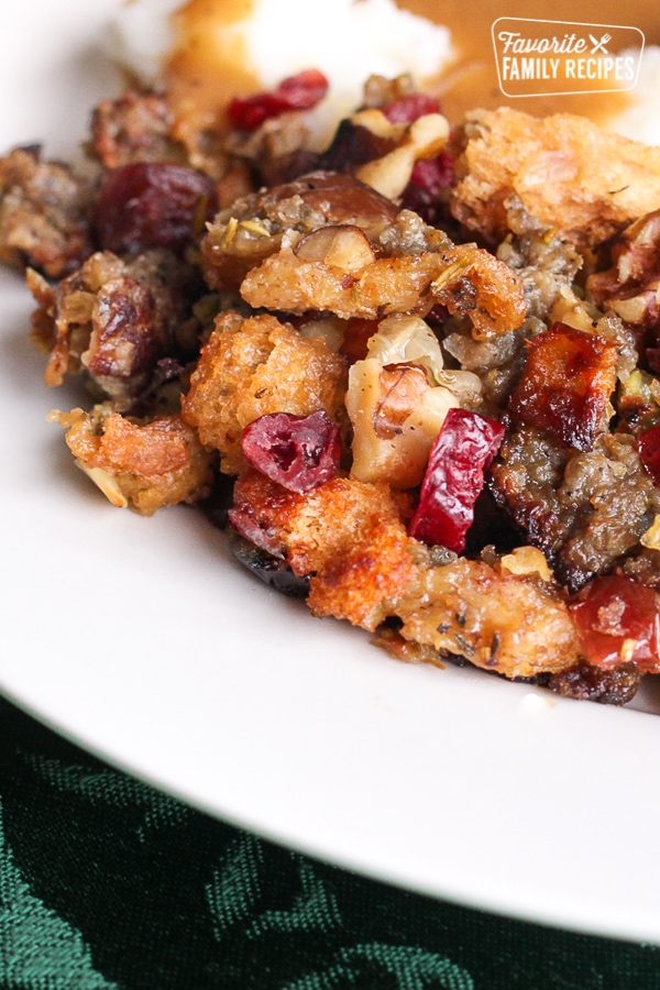Cranberry sausage stuffing with sausage, dried cranberries, apples, and bread cubes served on a white plate.