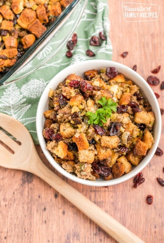 Cranberry Sausage Stuffing in a white bowl with a wooden spoon next to it