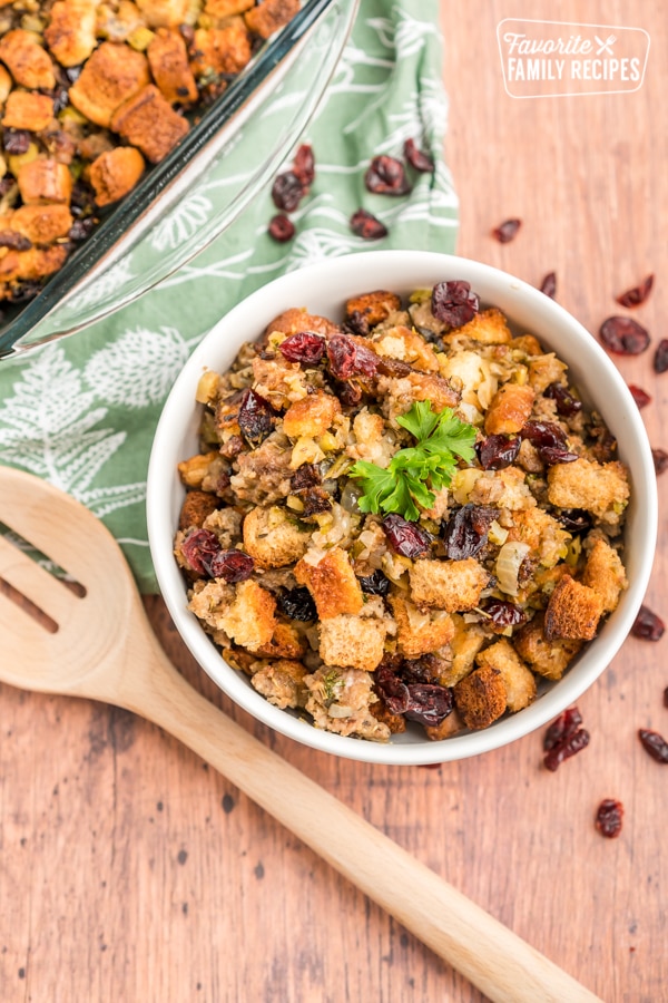 Cranberry Sausage Stuffing in a white bowl with a wooden spoon next to it