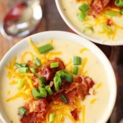 Potato soup in a bowl with bacon, cheese, and green onion as garnish