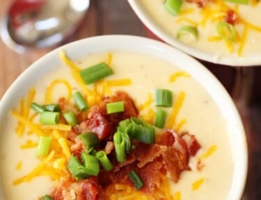 Potato soup in a bowl with bacon, cheese, and green onion as garnish