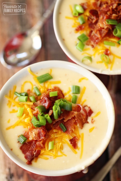 Potato soup in a bowl with bacon, cheese, and green onion as garnish