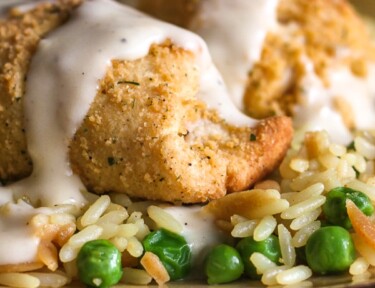 Easy Chicken Crescent Roll Ups over rice and peas on a plate.