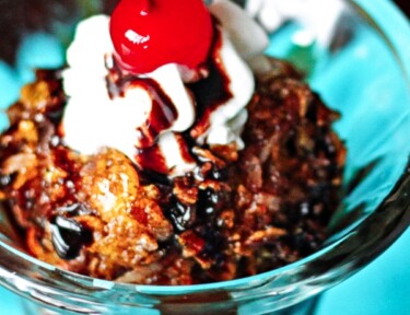 Fried Ice Cream topped with whipped cream and a cherry in a glass bowl.