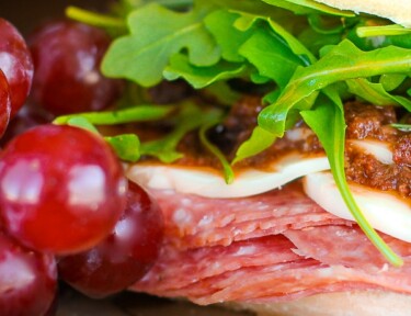 Close up of an Italian Sandwich with Olive Tapenade and grapes on the side.