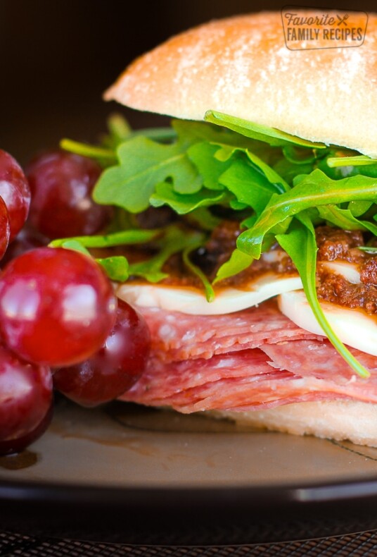 Close up of an Italian Sandwich with Olive Tapenade and grapes on the side.