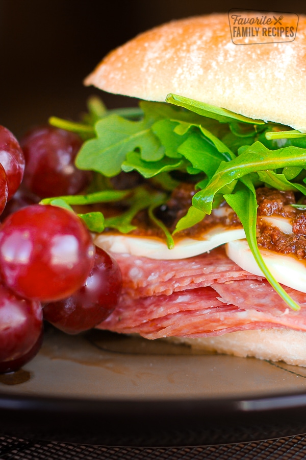 Close up of an Italian Sandwich with Olive Tapenade and grapes on the side.