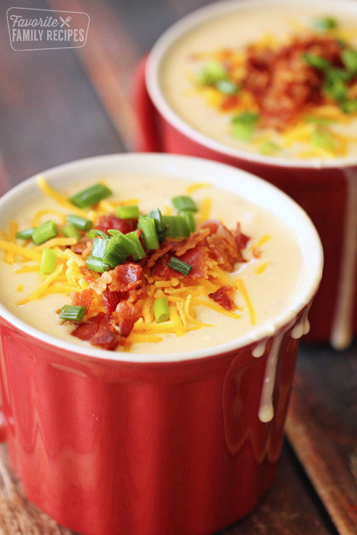 Potato soup in a cup with cheese, bacon, and green onion as garnish