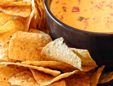 Easy Nacho Cheese Dip in a bowl with Tortilla Chips on the side.