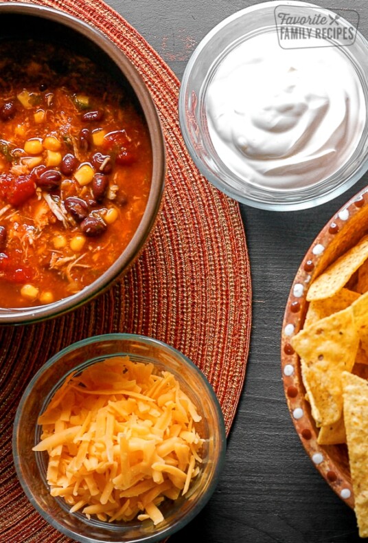 Southwest Taco Soup in a bowl with sour cream, cheese, and chips on the side.