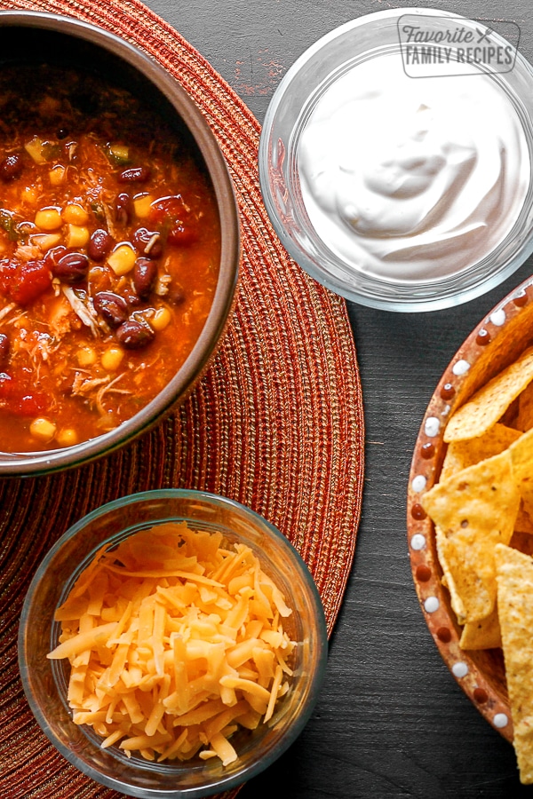 Southwest Taco Soup in a bowl with sour cream, cheese, and chips on the side.