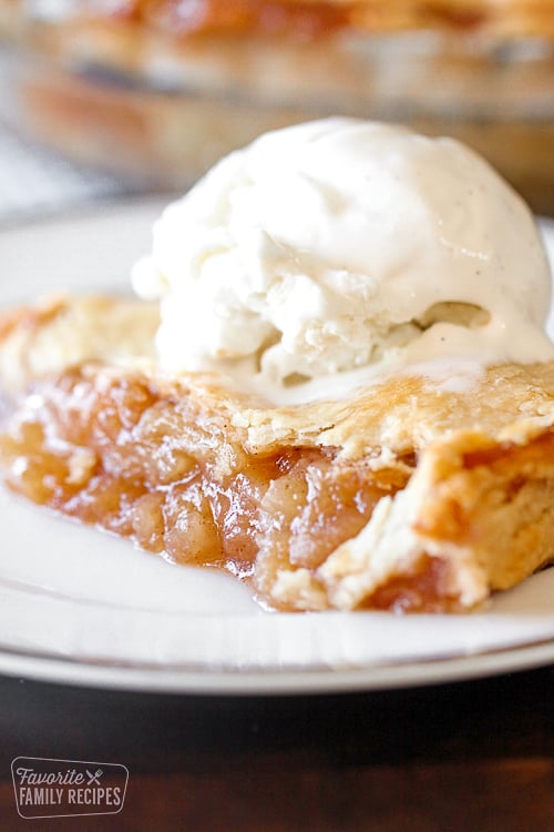 Slice of apple pie with ice cream over the top.