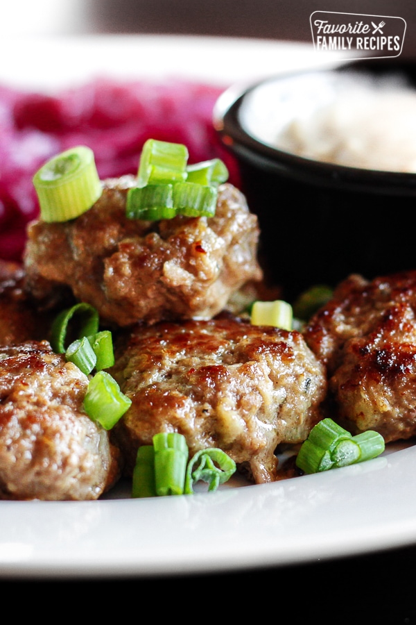 Frikadeller Danish Meatballs sprinkled with green onions served with red cabbage on a white plate